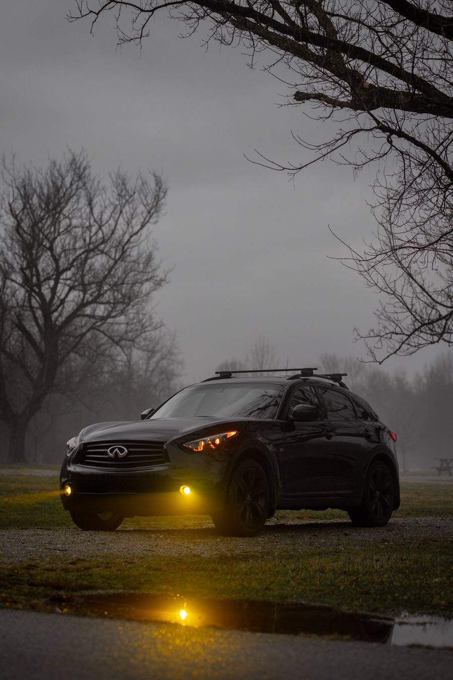 Black Infiniti QX70 in fog at dusk with EVO TRI headlights and amber fog lights